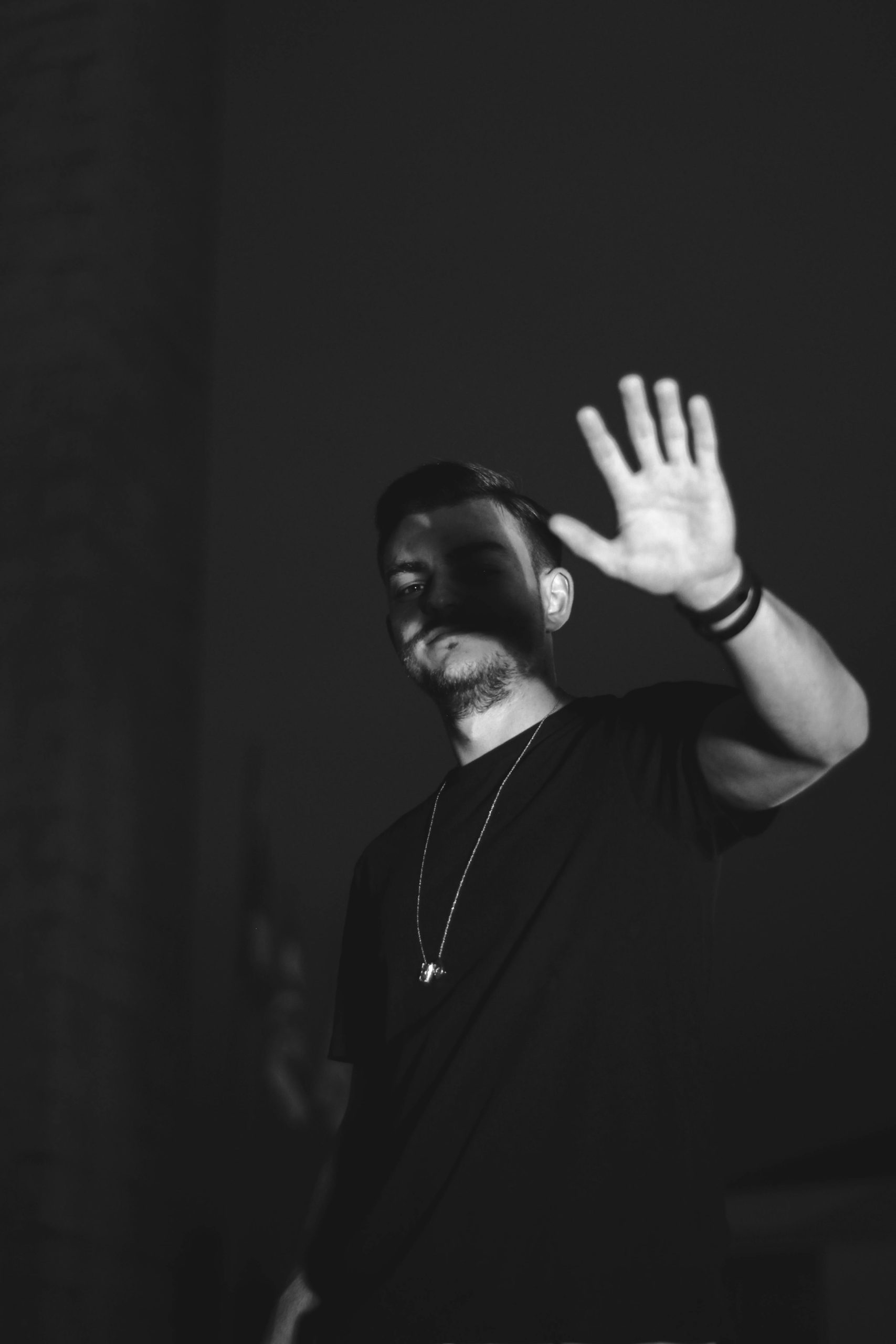 Black and white portrait of a man raising his hand, creating a mysterious and artistic effect.